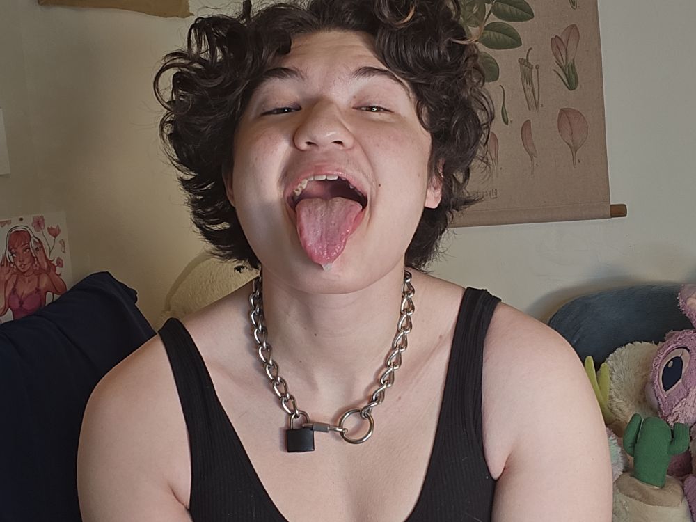 A picture of Cherry with his mouth open wide and his tongue stuck out. He is wearing a black tank top and metal choker.