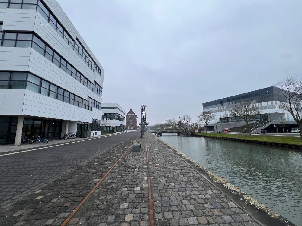 photo of the rhine-waal campus in cleves, featuring the spoy canal, a bridge and modern buildings under a gloomy grey sky