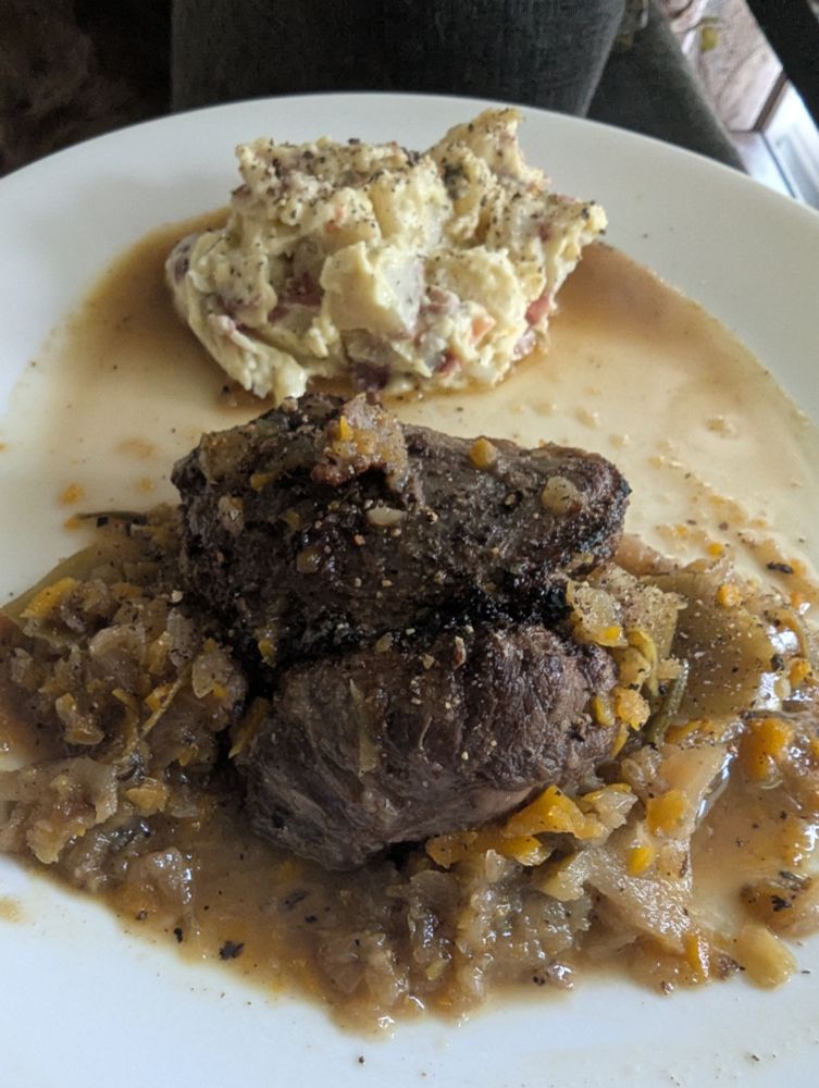 One cheek served on top of the apple and mirepoix mash from the Dutch Oven, in the foreground.
In the background is a serving of potato salad. 