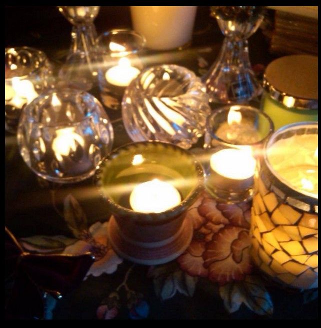 Photo taken of a candle scape where the warm glow of live candles dances in various glass votive holders