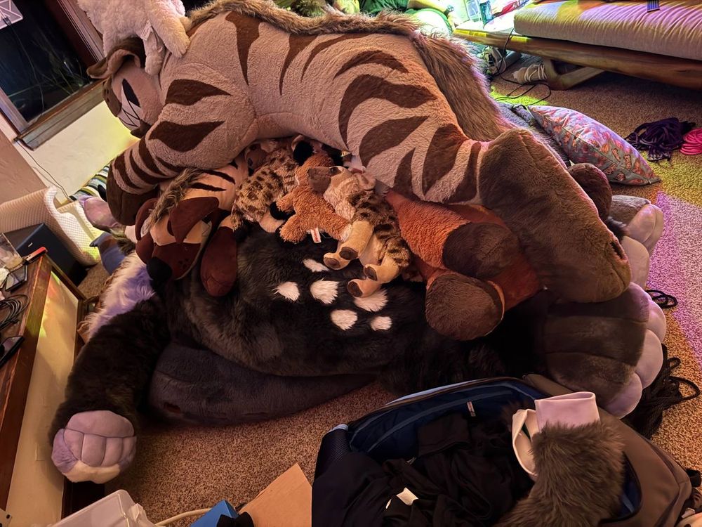 All three images show a big pile of plushes, with the Azzurra, a plush suit jackelope at the bottom. Most of the pile is hyena plushes, including a huge 6-ft hyena plush at the top.

Side view, one of the handpaws of the plush suit is visible