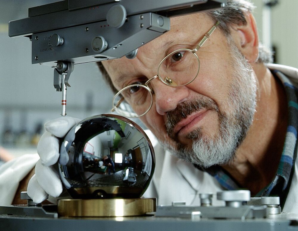 Silicon sphere used in the Avogadro project being inspected by Achim Leistner, master optician at the Australian Centre for Precision Optics (part of the CSIRO). The sphere, which has a diameter of about 93.6 mm, was cut from a single crystal of 99.9995% pure silicon-28 and has a mass of 1 kg. The number of atoms in the sphere has been calculated using X-ray crystallography with an uncertainty of less than 2×10-8. It is round to within one part in two million.