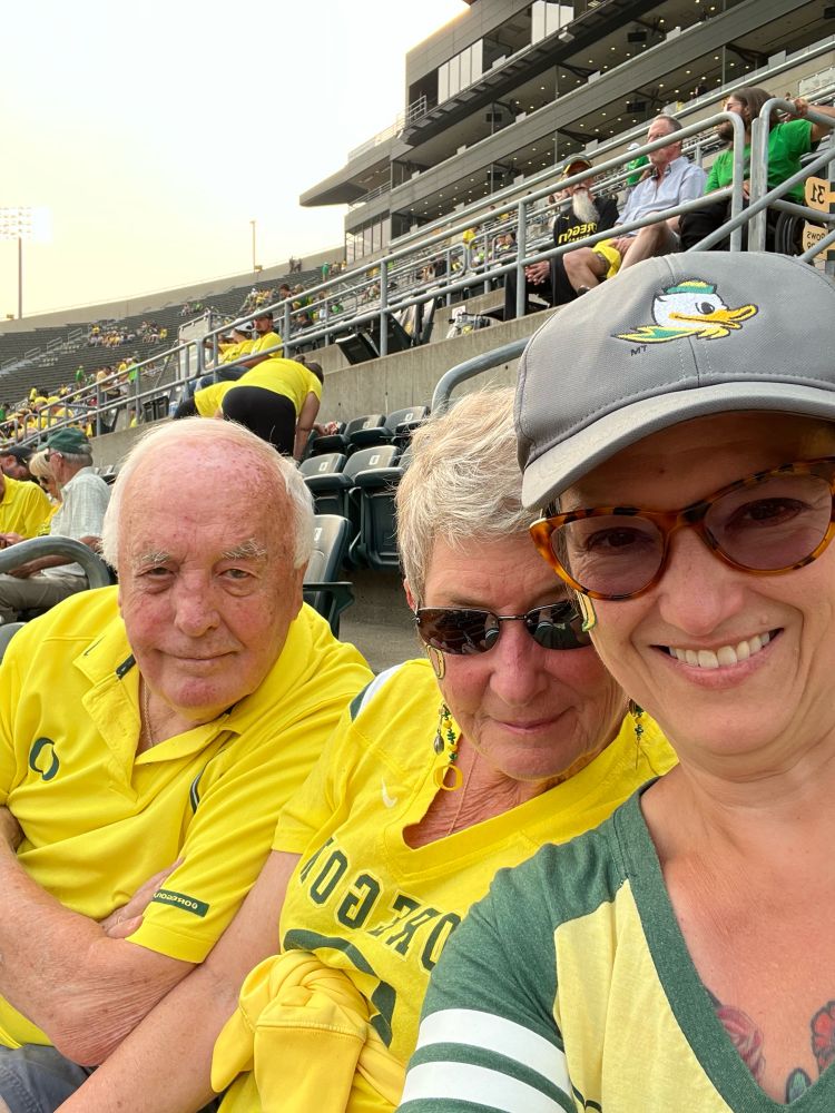 Family wearing yellow Oregon Duck attire at a football game at Autzen Stadium
