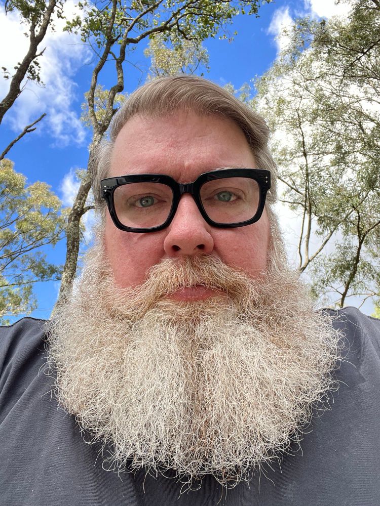 The account holder — bearded, bespectacled, white and 49 — sitting among native Australian trees on a pleasant day