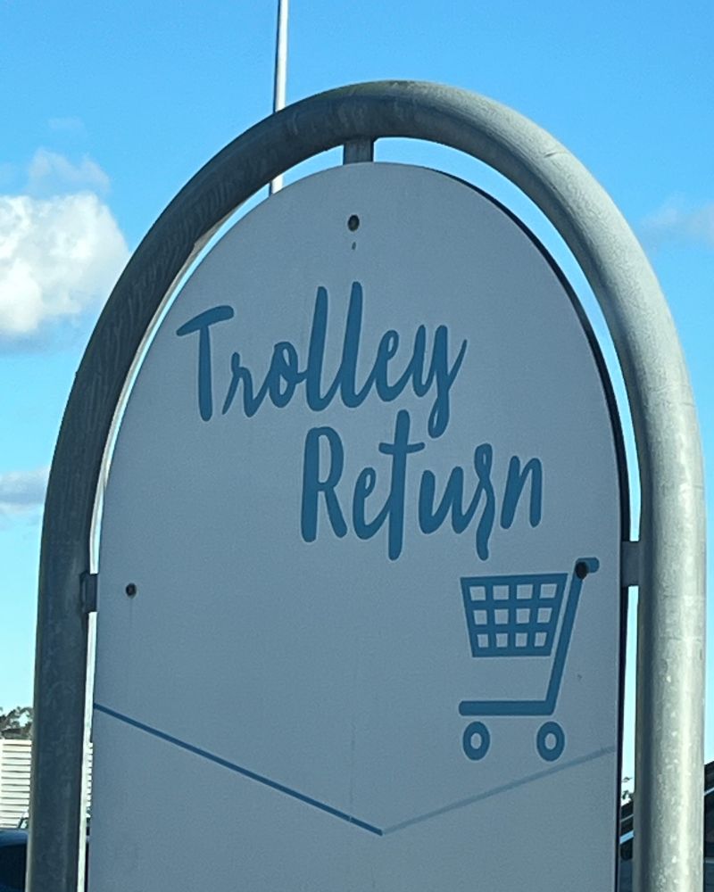 A sign saying “trolley return” in a whimsical, white-woman font