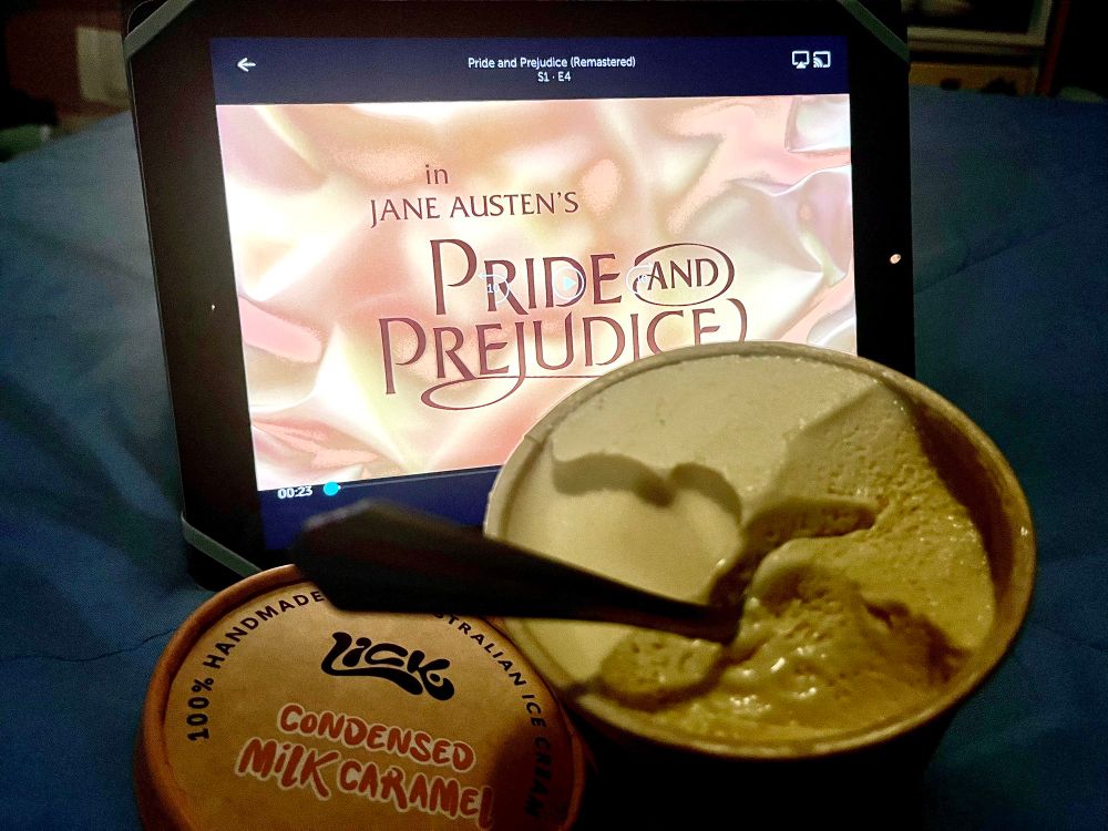 An iPad with the opening titles of the BBC Pride and Prejudice, sitting up behind an open tub of ice cream