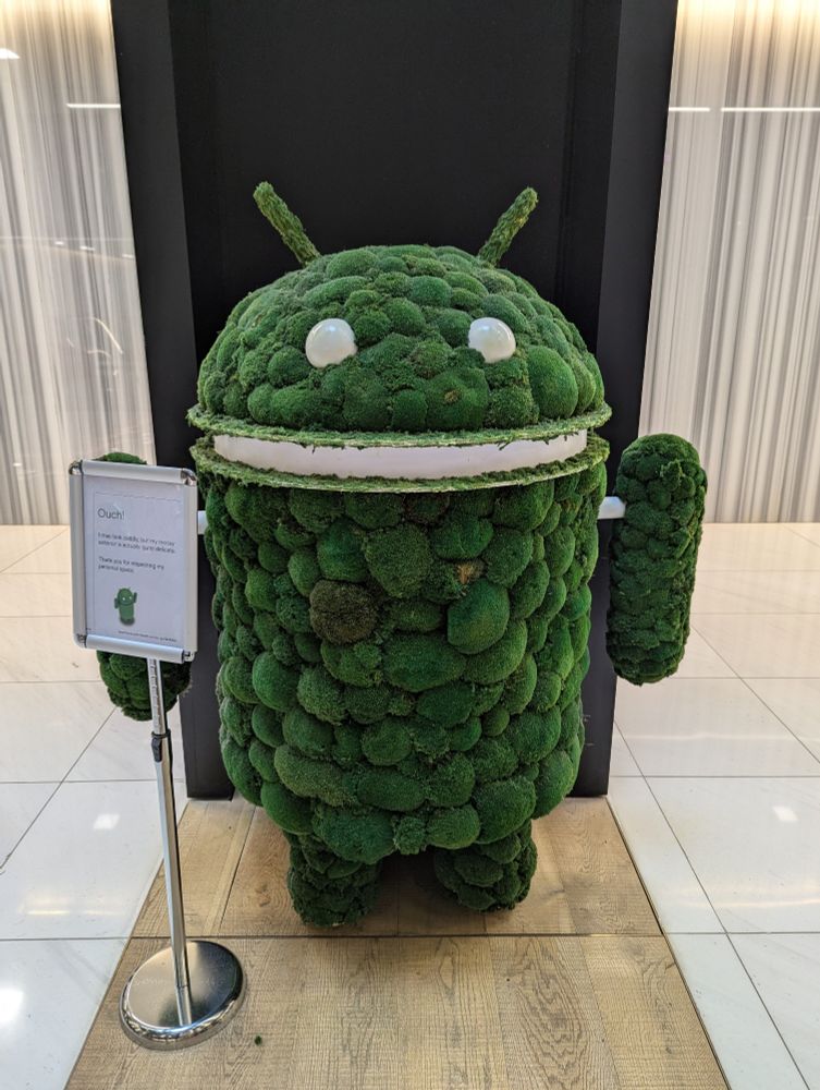 Android mascot made out of moss with a sign next to it