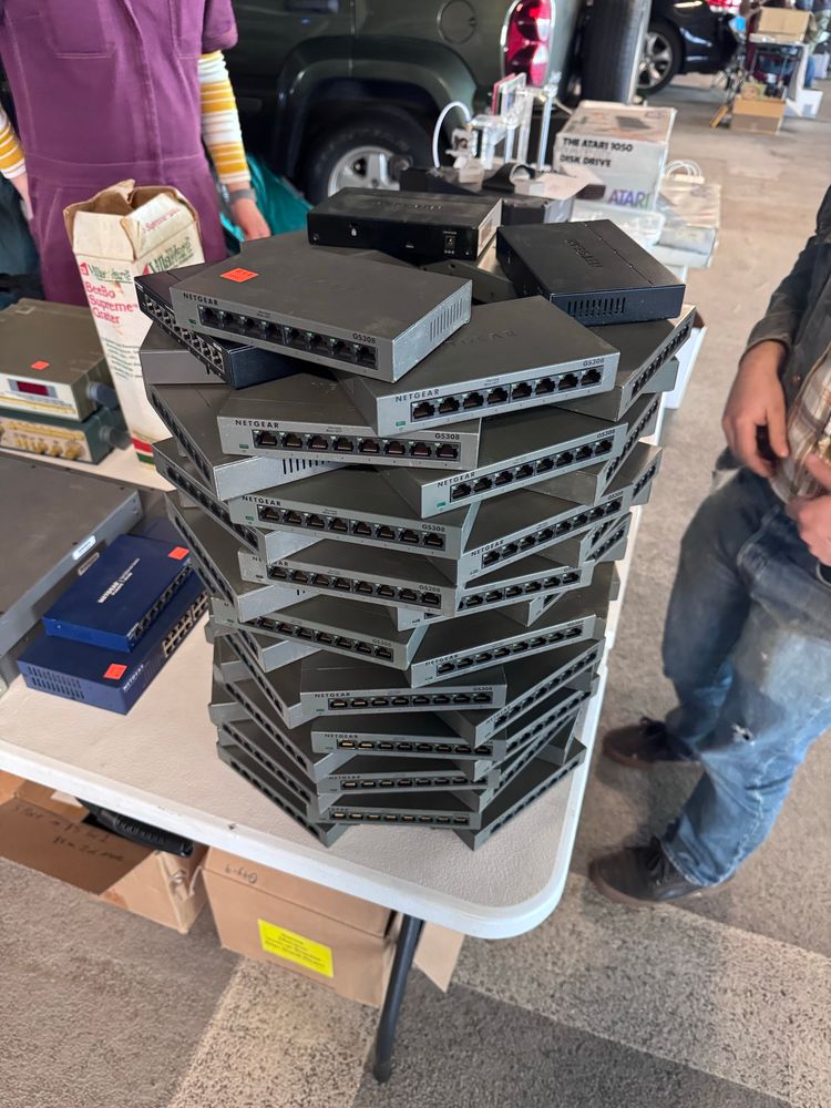 A huge stack of 8 port Netgear switches stacked artistically on a table