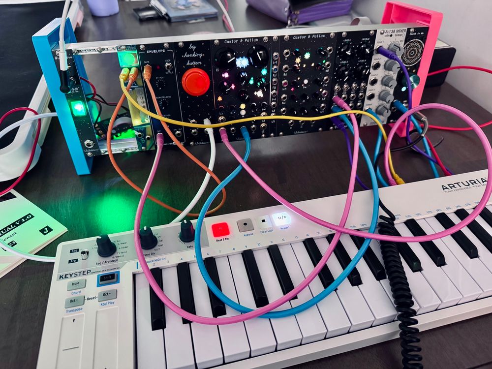 A mess of patch cables plugged into a small Eurorack synth and an Aturia Keystep keyboard