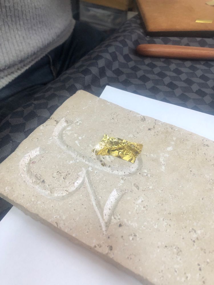 Gravure sur pierre en train d’être doré à la feuille 