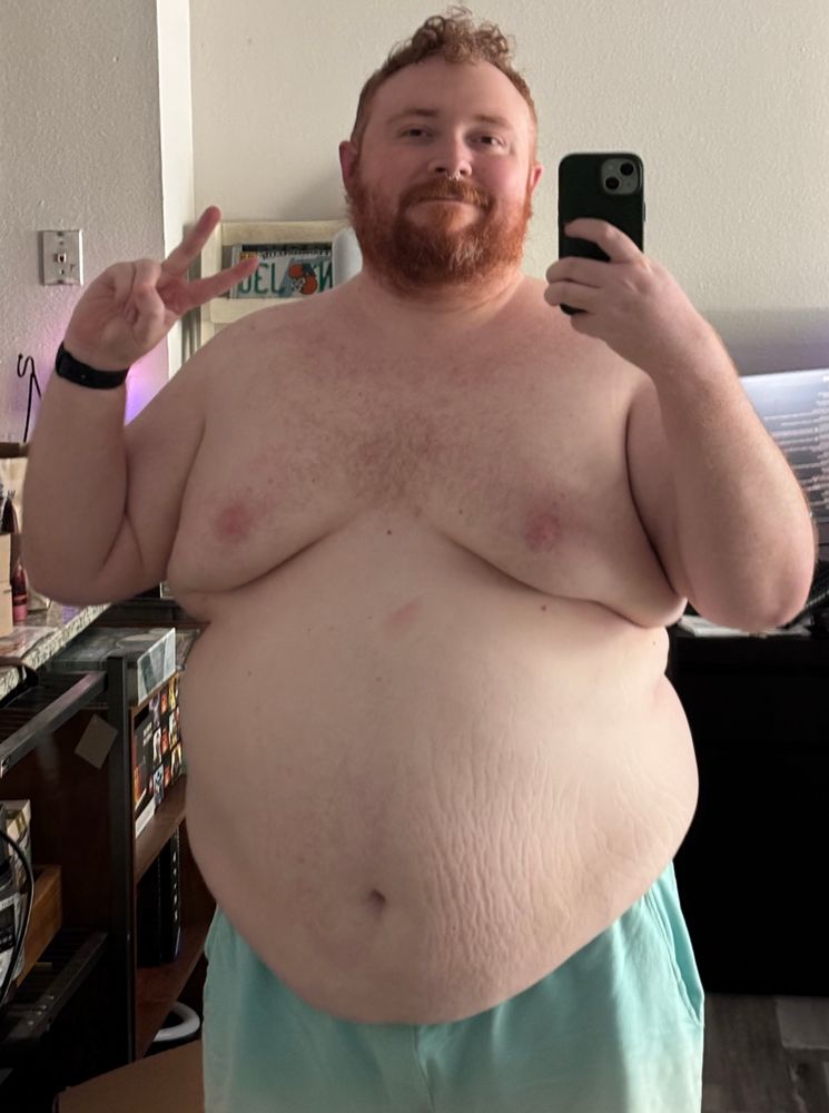 Cooper standing with his shirt off giving a peace sign