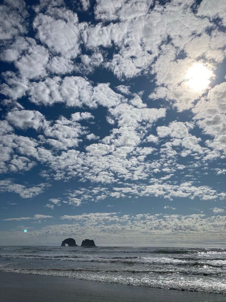 Twin rocks viewed from Rockaway Beach, Oregon. Clouds scraping the top of the big sky in late afternoon sun. 