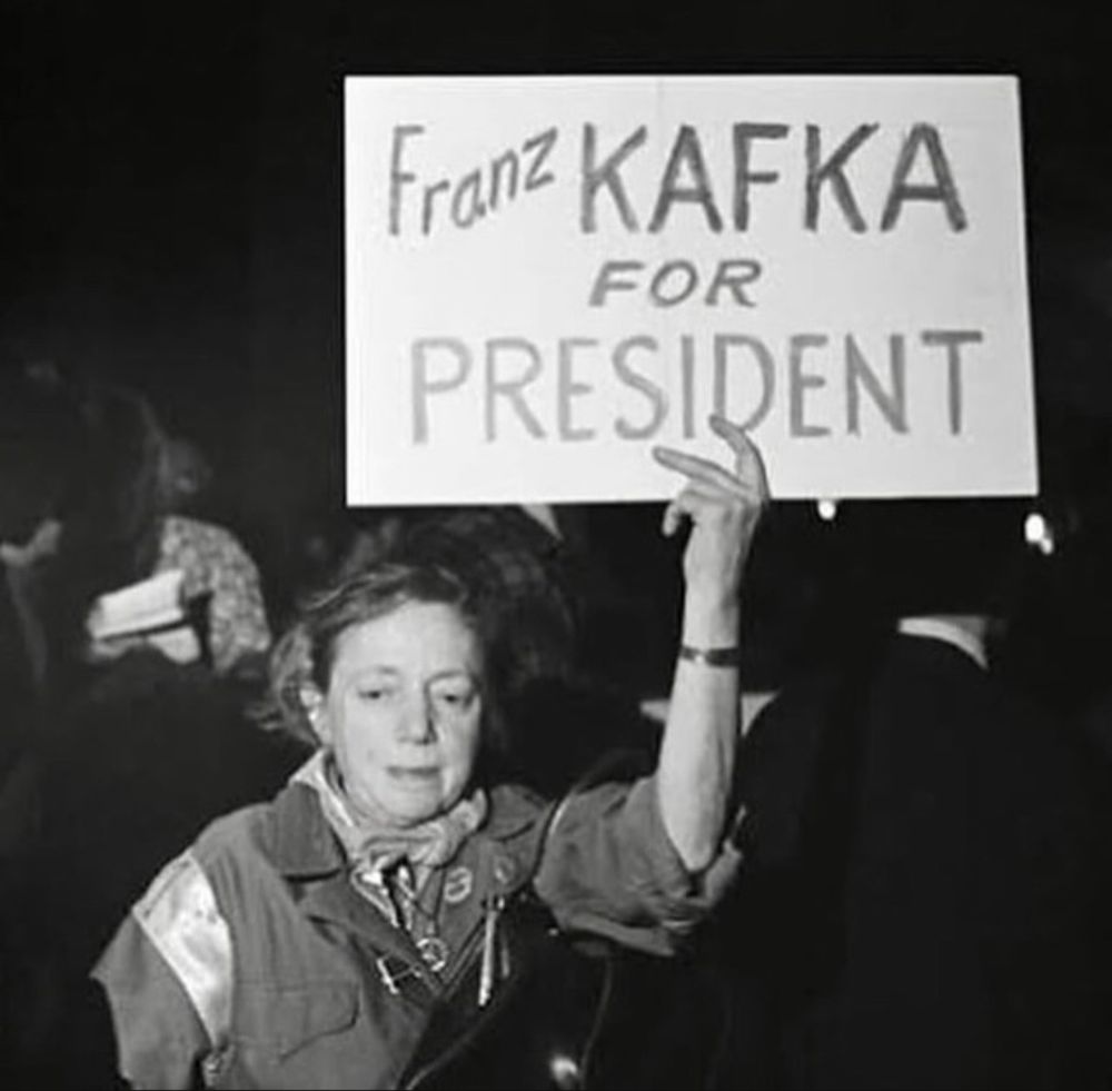 Photo d'une manifestante arborant une pancarte avec l'inscription : Franz Kafka for president.