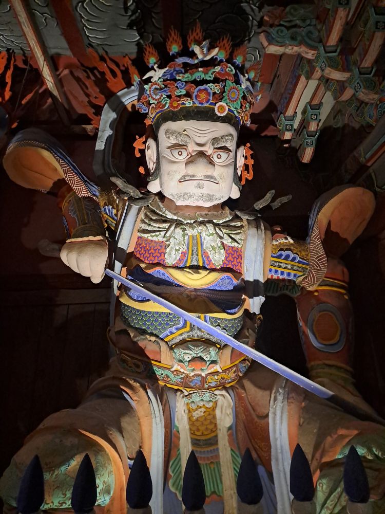Statue de gardien, le sabre à la main, à l'entrée d'un temple bouddhiste. Photo de nuit.