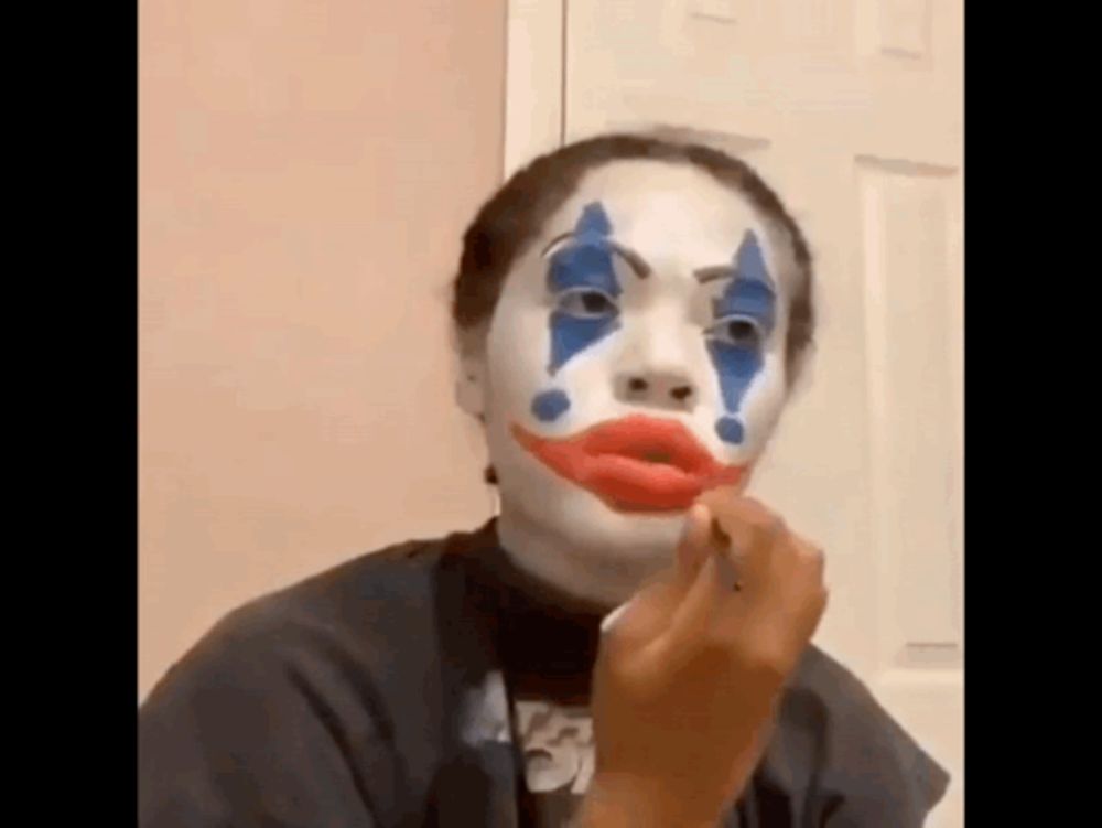 a woman is wearing a clown makeup and applying lipstick .