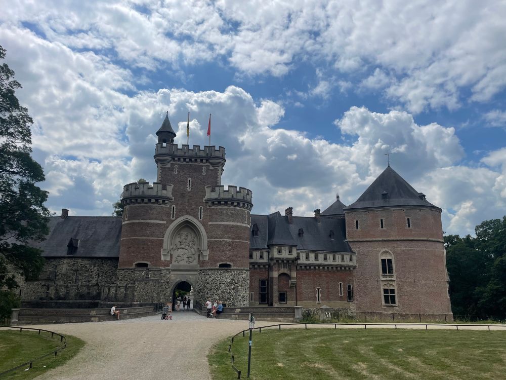 The front of a castle under a cloud-dotted summer sky. It’s the castle of Gaasbeek by Brussels, which its last owner (the Marquise Arconati-Visconti, the daughter of a French journalist) decorated in a playful mock-medieval style. It’s great! 