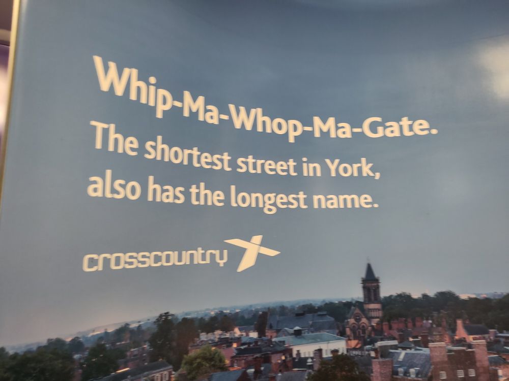 A wraparound poster (as it happens, in the toilet of a Crosscountry train) showing an aerial photo of York's historic core with the caption. "Whip-ma-whop-ma-gate. The shortest street in York, also has the longest name."