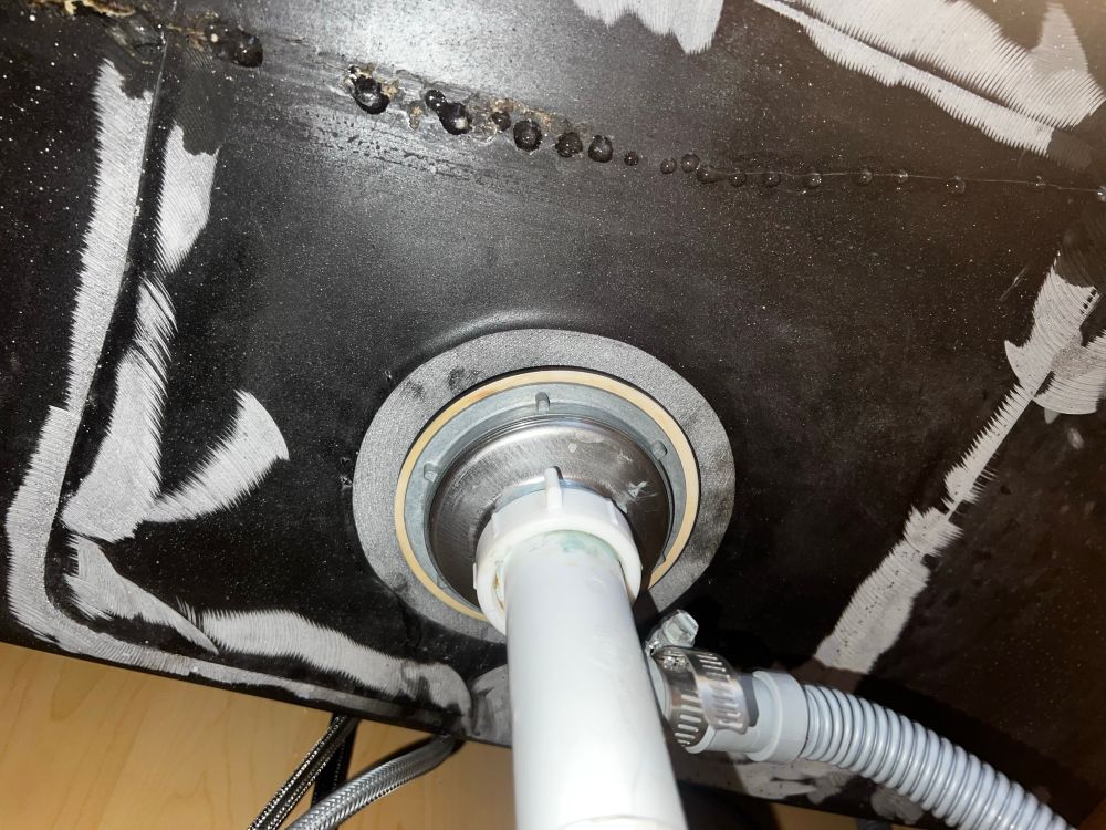 Underside of a sink with drips of water through it 