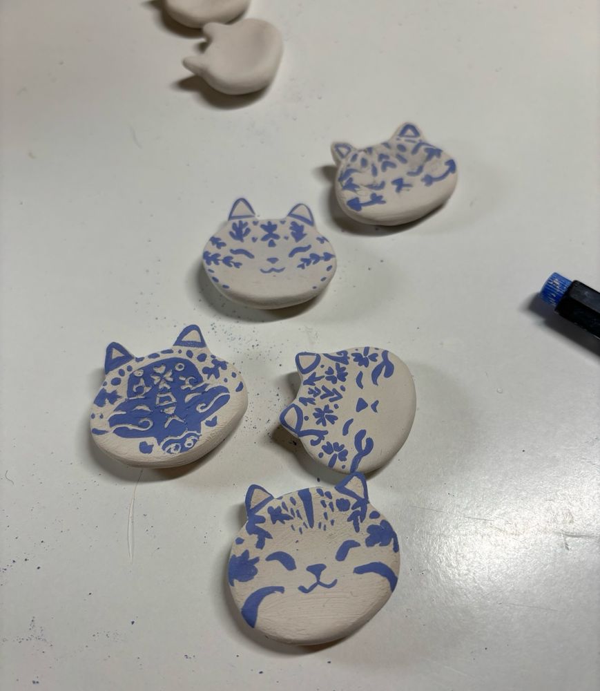 Porcelain worry stones shaped as a cats face with blue details 