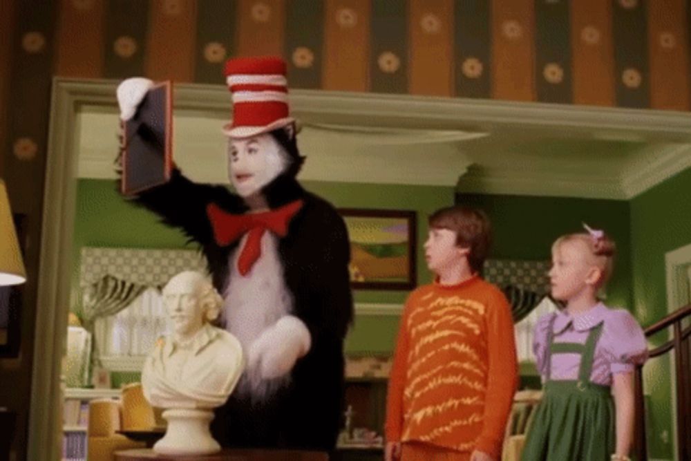 cat in the hat is holding a book in front of a statue