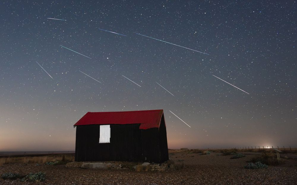 A few meteors from the Perseid shower over the red-roofed hut at Rye Harbour nature reserve