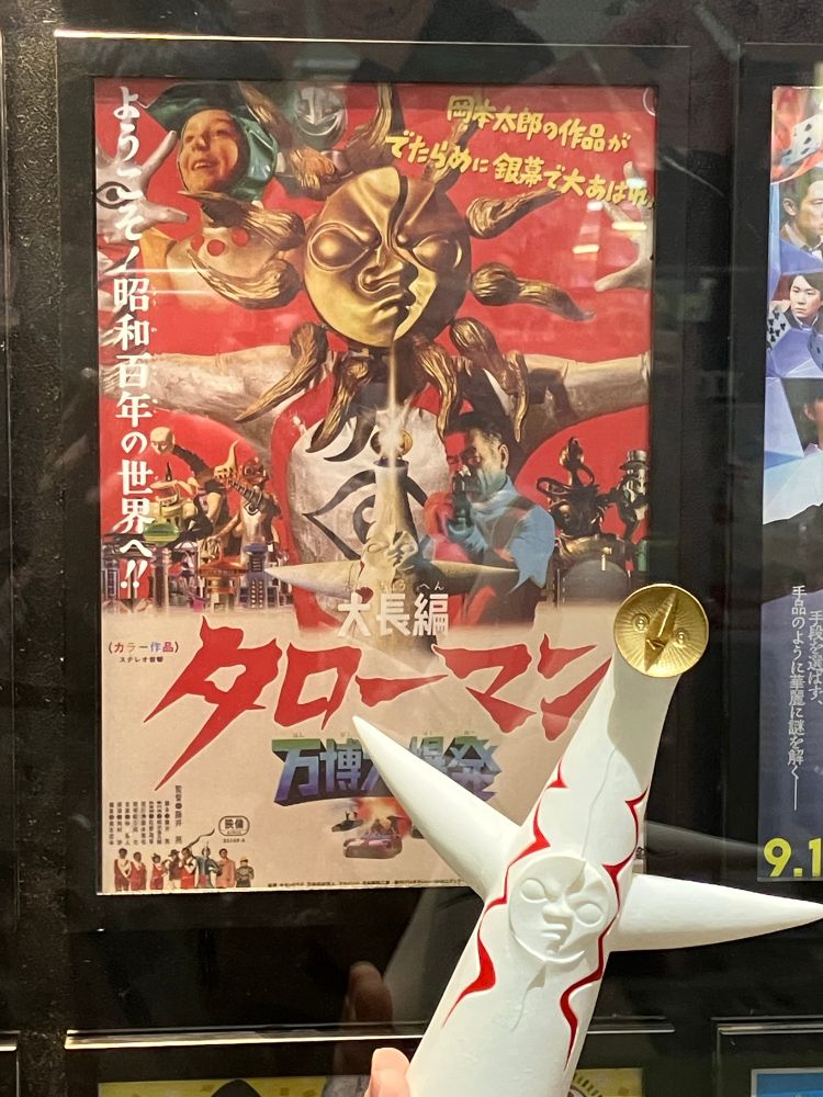 持参した太陽の塔のソフビ人形と、映画館に貼り出された『大長編 タローマン 万博大爆発』のポスター