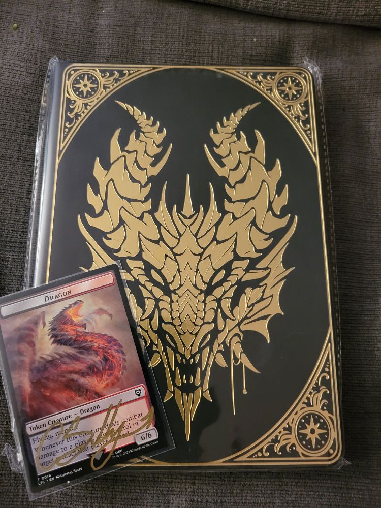 Picture of a black and gold journal featuring a red dragon face and a dragon token from Magic the Gathering.