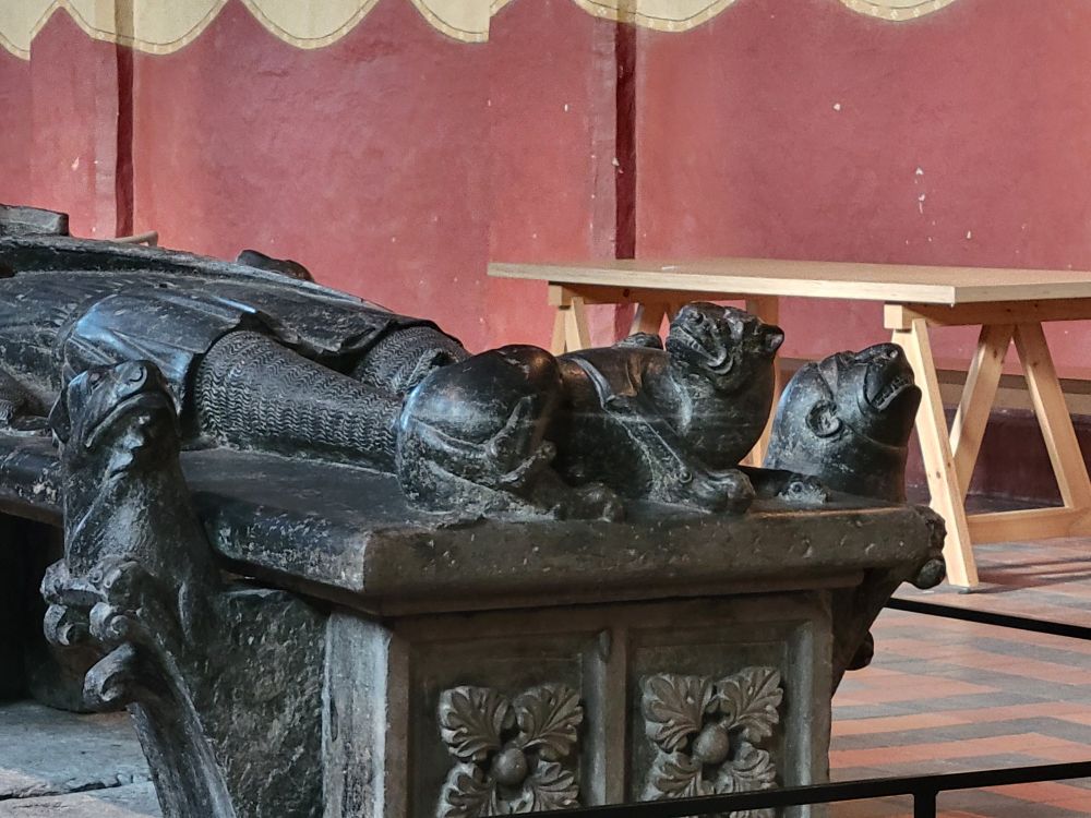 Burial statue with a dog like figure laying at the foot of a man. 