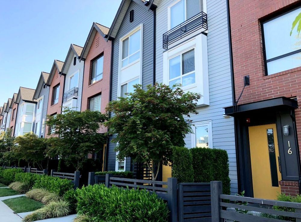 Some tall and skinny row houses in shades of blue and red in Burnaby, BC that are "salt box" inspired