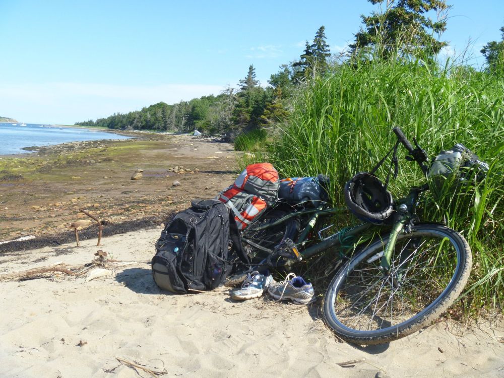 Photo of my green bike on the beach on McNabs Island with camping gear next to it.