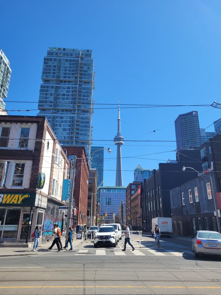 The CN tower in a blue sky with streetcar wires in the foreground 