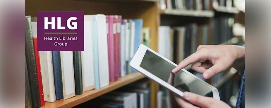 HLG AGM screenshot.  The hands of a person holding a tablet in front of a bookshelf with books.