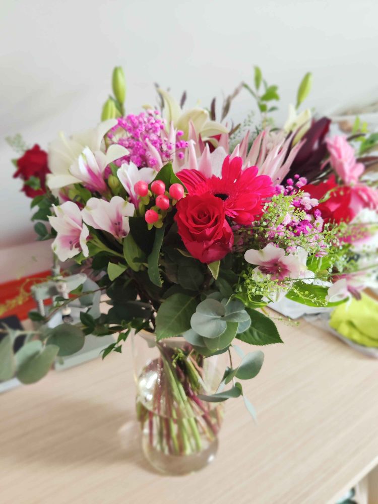Vibrant photo of a gorgeous bouquet featuring an arrangement of various flowers, such as lilies, roses, hypericums, baby's breath, and more!