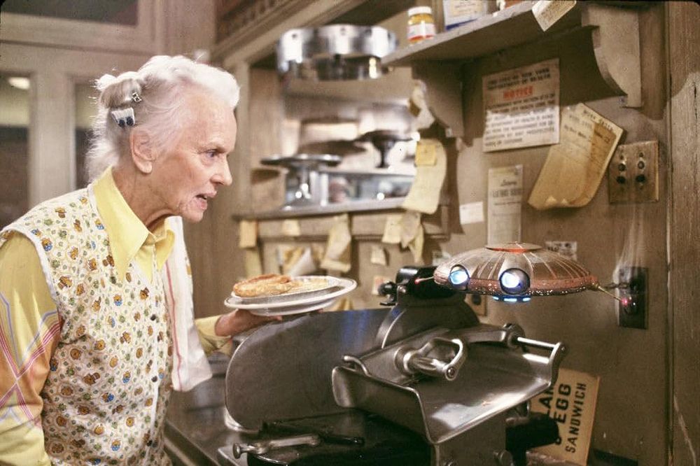 Still image of Jessica Tandy and an extraterrestrial in a diner kitchen from the 1987 film Batteries Not Included.
