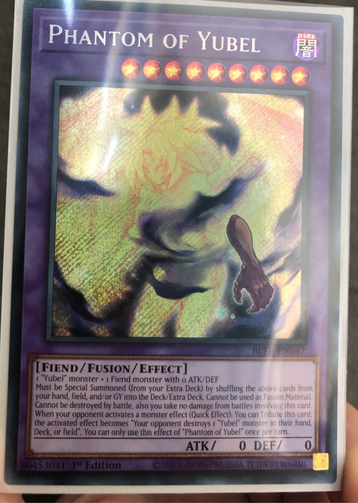 Phantom of Yubel, a Yugioh card which is very expensive. The monster on the artwork is a yellow glowing non-binary demon.