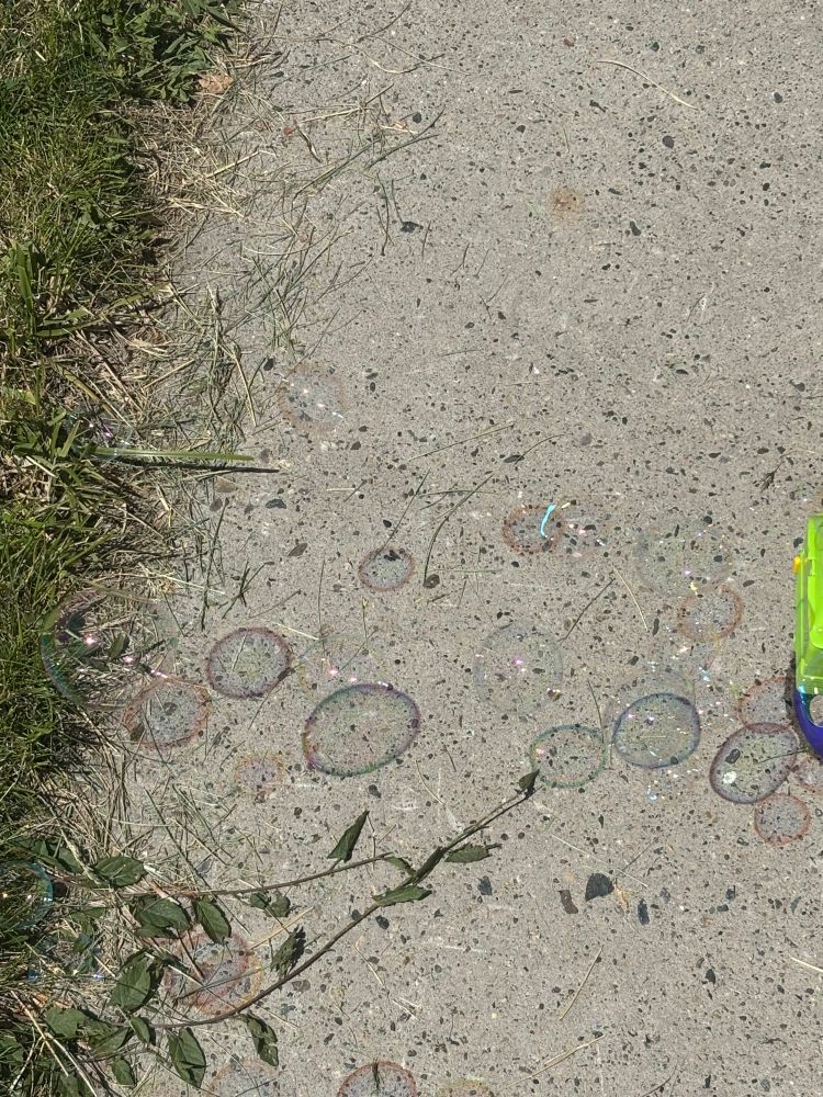 A picture of bubbles from a bubble maker the smaller bubbles cast red and orange “shadows” while the larger cast green, blue, and purple.
