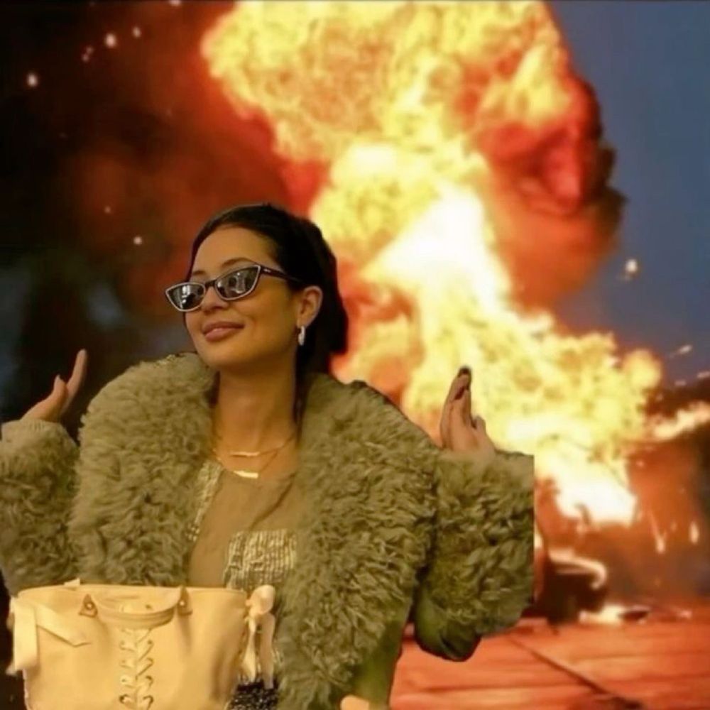 Woman in sunglasses and fur in front of flames