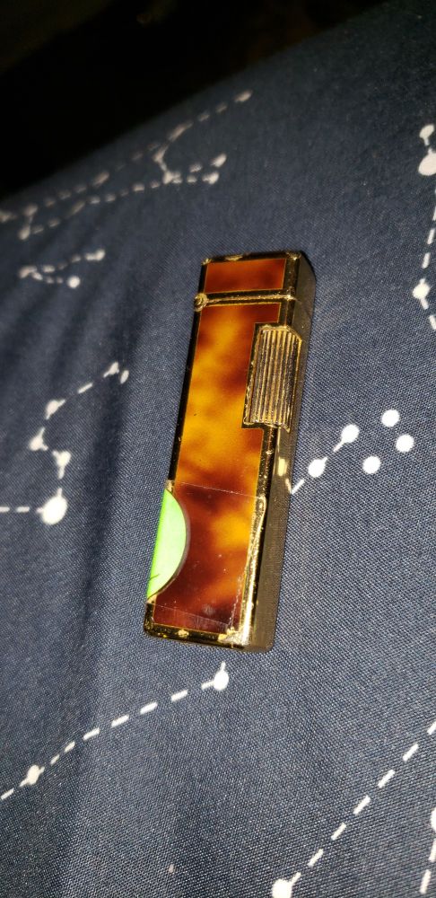 A slim colibri lighter (exact model unknown) with a tortoise shell pattern and golden trim and flint wheel