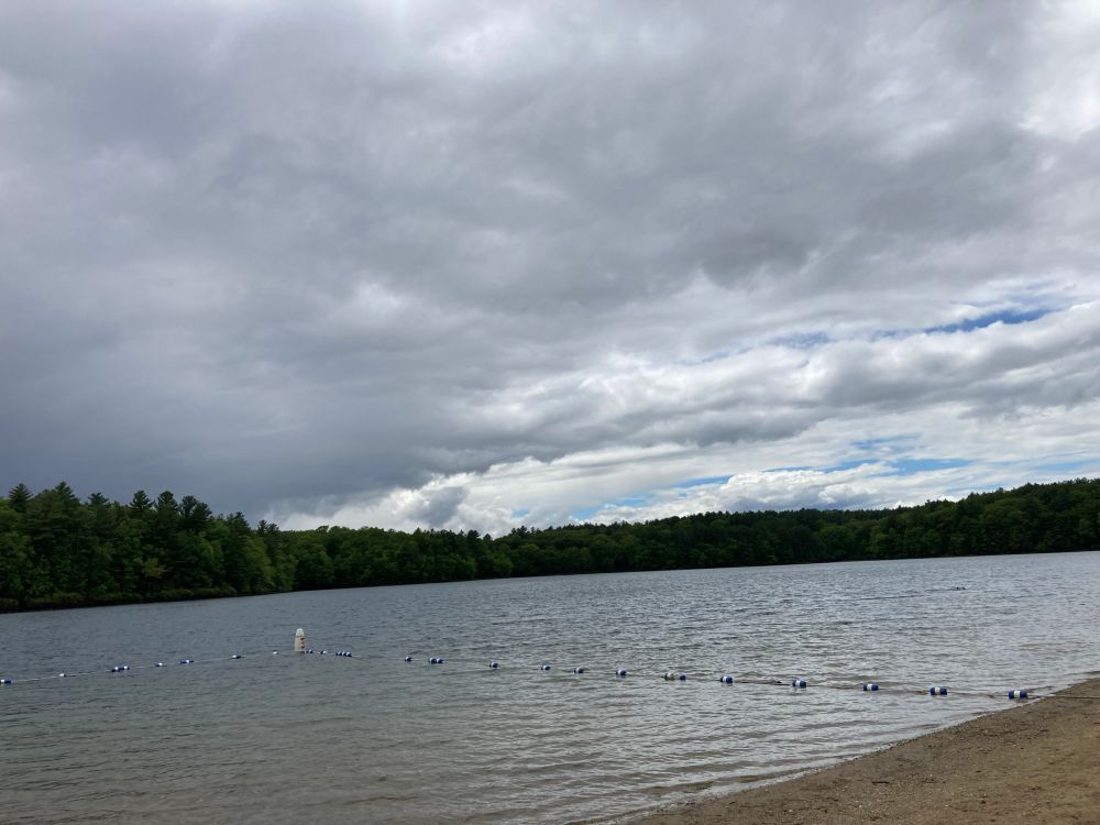 Clouds above Walden Pond in Concord MA with blue sky on the horizon. 