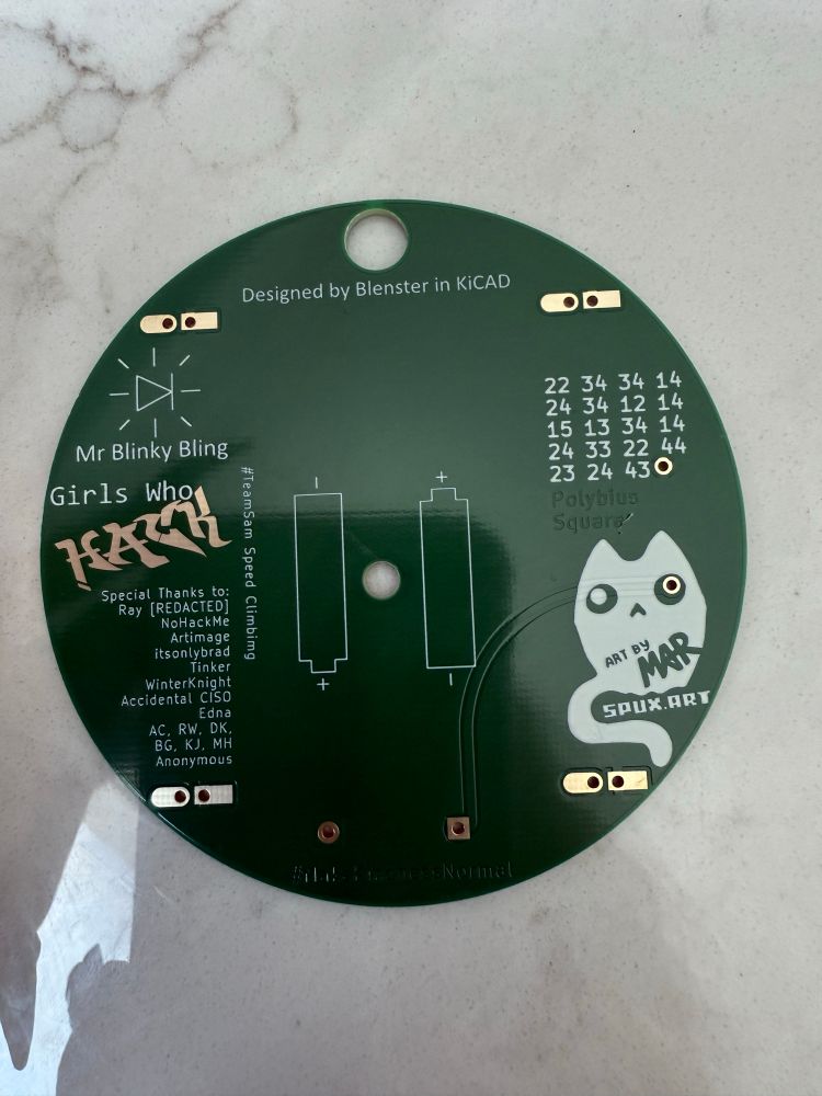 Back side of a circular green printed circuit board (PCB) with various white silkscreen graphics and text. At the top, it reads ‘Designed by Blenster in KiCAD.’ On the left, there’s an LED symbol labeled ‘Mr Blinky Bling’ and the text ‘Girls Who Hack’ with a graffiti-style font. Below that is a list of ‘Special Thanks’ names. The center shows battery polarity diagrams for two AA batteries. On the right side, there’s a ghost-like character labeled ‘ART BY MAR’ with the URL ‘SPUX.ART.’ There’s also a grid of numbers labeled ‘Polybius Square?’ and gold-colored solder pads.