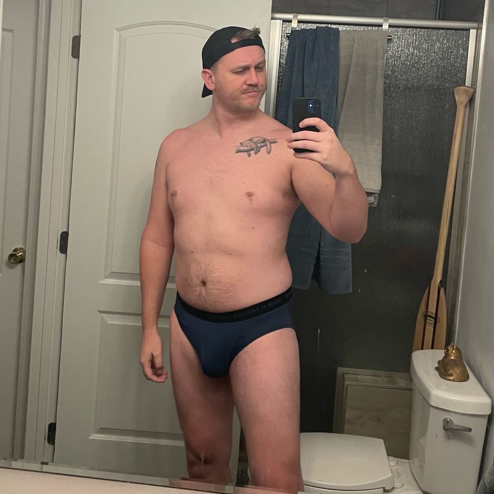 Guy in blue briefs with tattoos and baseball hat