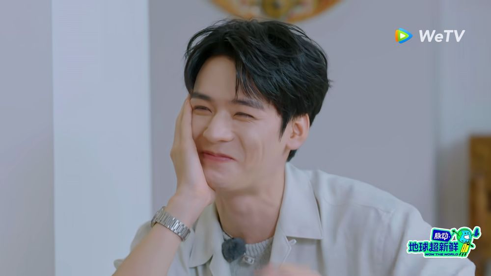 Gong Jun with his face resting on his hand, trying (and failing) not to laugh