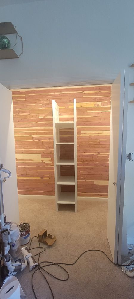 The same closet with no clothing, but with cedar wood panels and white shelving. 