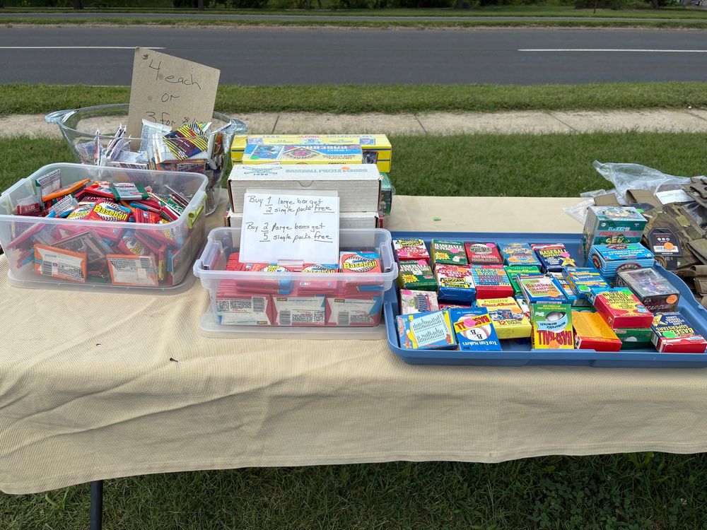 An outdoor flea market table with 30 to 40 year old packs of baseball cards.