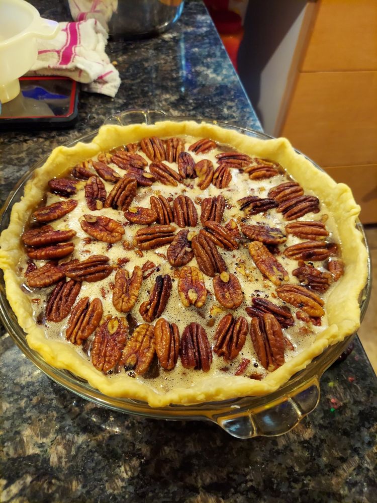 Part three of the pie - the decorative pecans in a sort of circular pattern on top of the custard/pecan mixture that constitutes the pie filling.
