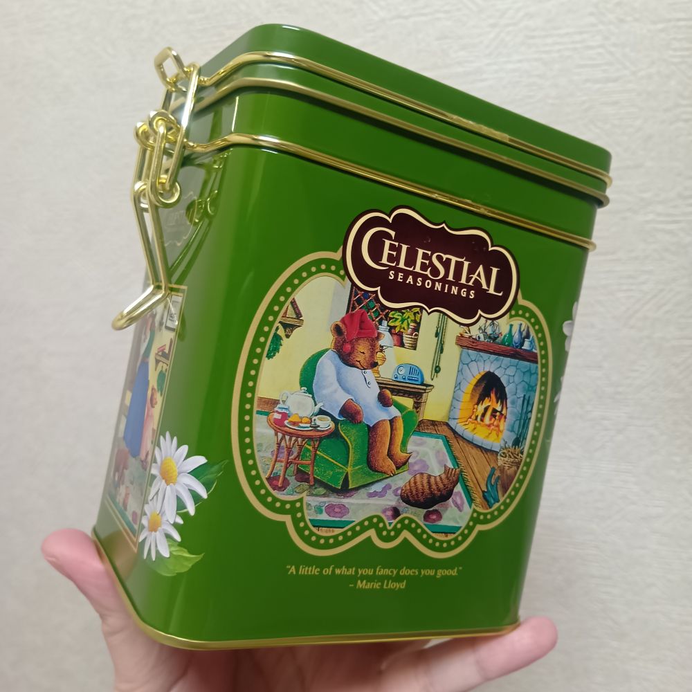 セレッシャルハーブティーの緑色のブリキ缶。スリーピータイムのパジャマ姿の暖炉前でくつろぐ熊の絵などが描かれている。