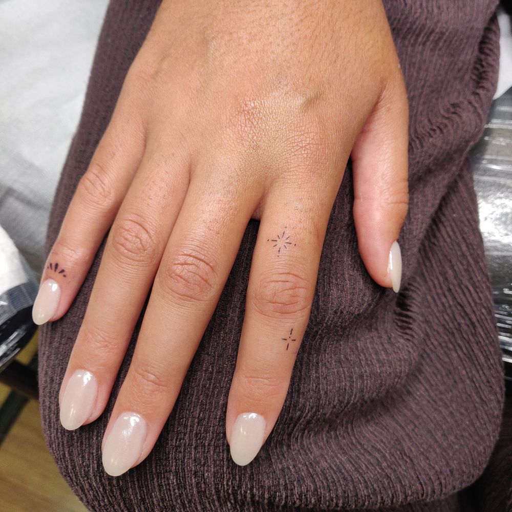 Photo of a hand with small sparkle stickers on a pointer finger and a small embellishment on the pinky below the nail. 