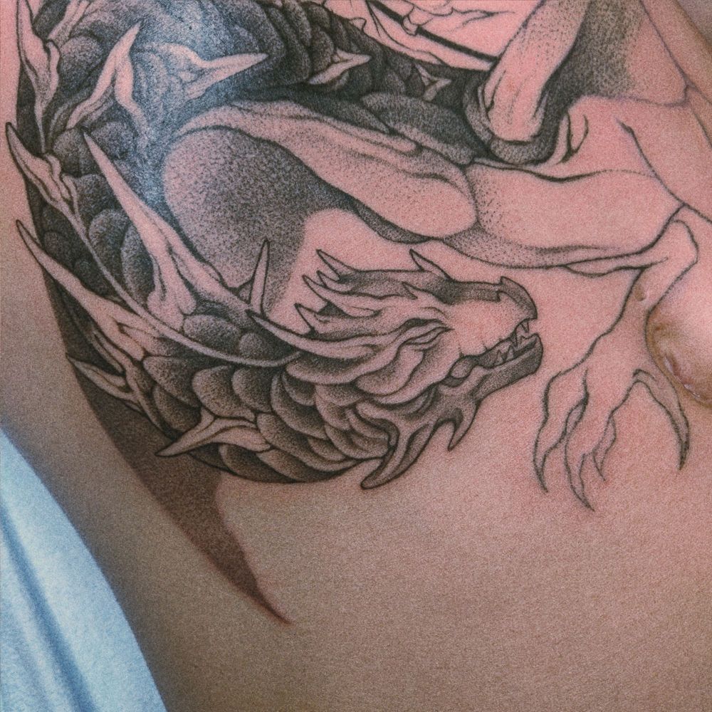 Half shaded tattoo of a dragon on a stomach. 