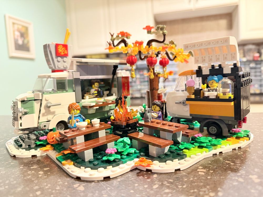 With coffee tuk tuk and noodle truck, the Vintage Food Truck Festival by Isibricks reminds you of a crisp autumn day in a small park, including two picnic tables, pretty fall foliage, Chinese lanterns, and a campfire.