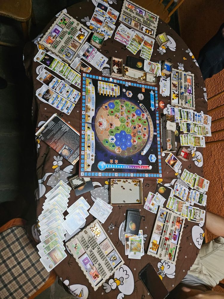 Mesa com cartas e o tabuleiro do jogo Terraforming Mars
